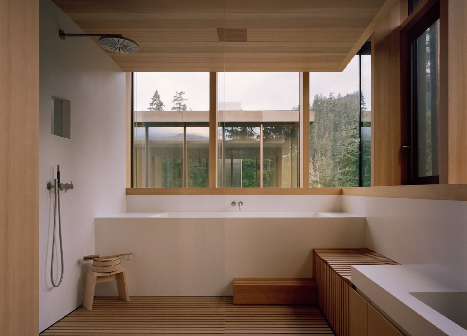 A serene wet room in warm wood with windows onto the pines